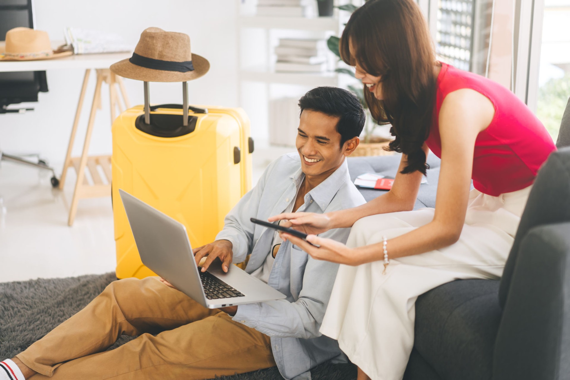 Young adult southeast asian couple using laptop for getting ready for holidays travel trip