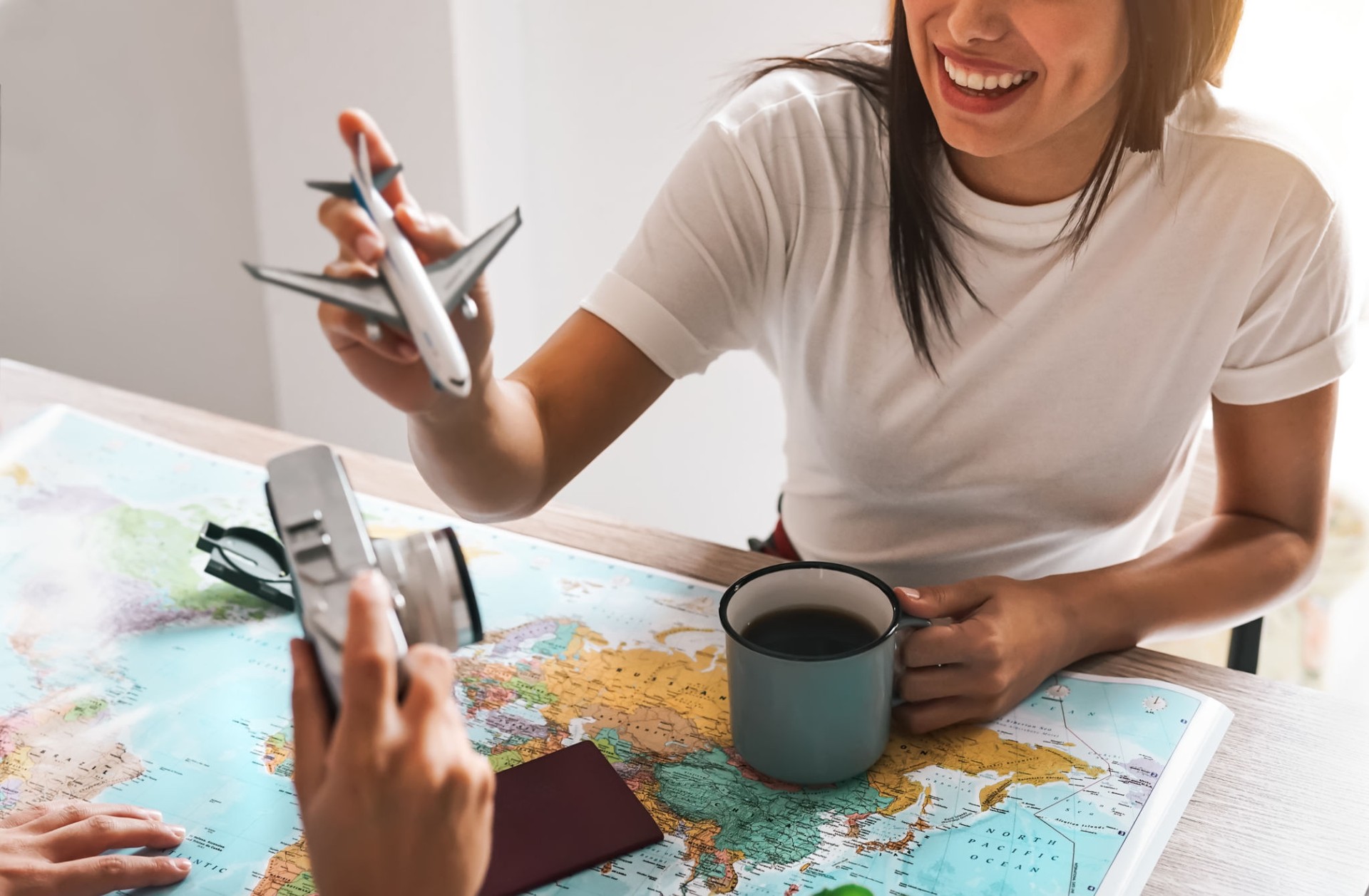 Happy couple planning next travel destination using world map - Young playful people having fun and getting ready for vacation - Relationship and Traveling lifestyle concept